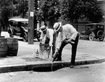 A bolttulajdonos saját maga önti a csatornába az alkoholos üvegeinek tartalmát (1920)