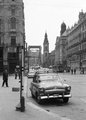 Volga taxi a Ferenciek terén (Felszabadulás tér) a Szabad sajtó út felé nézve. Háttérben az épülő Erzsébet híd (1964)